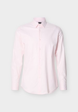 Moška srajca svetlo rožnate barve z dolgimi rokavi, spredaj z gumbi in klasičnim ovratnikom na enobarvnem svetlem ozadju.
