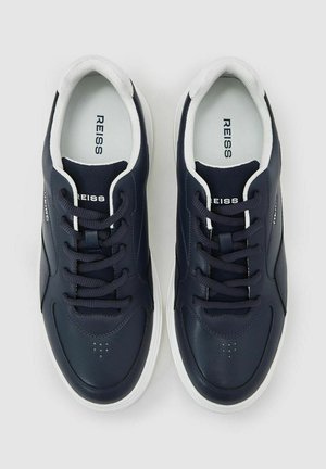 Adidași de piele bleumarin cu accente albe, vârf rotund și șireturi plate. Model texturat pe partea superioară și perforații pentru respirabilitate.