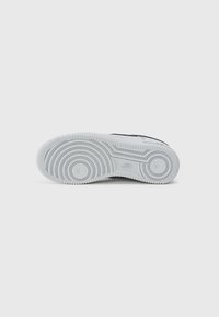 Nike zābaku zole baltā gumijā, ar teksturētu virsmu un apļveida rakstiem, kā arī iegarenu "Nike" logotipu netālu no papēža zonas.