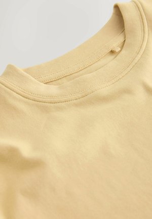 T-shirt en coton jaune clair avec un col rond, une texture lisse et des manches courtes, présentant une finition soignée sur l'ourlet et le col.