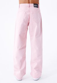 Jeans de mezclilla de pierna ancha en rosa claro con una cintura alta, que presentan dos bolsillos traseros y una etiqueta de marca negra en la cinturilla.