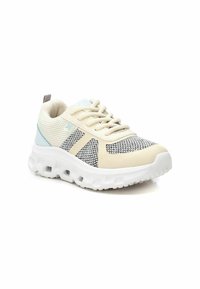 Zapatilla deportiva beige con parte superior de malla, acentos grises y suela blanca. Presenta cordones redondos y un cuello acolchado para mayor comodidad.
