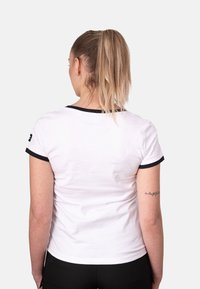 Camiseta blanca de manga corta con ribete negro alrededor del cuello y las mangas, diseño ajustado y textura de tela suave.