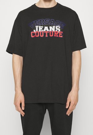 T-shirt en coton noir avec un imprimé graphique audacieux "VERSACE JEANS COUTURE" multicolore sur le devant. Manches courtes, coupe décontractée.
