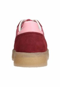 Rode suède sneakers met een roze hielsectie, witte veters en een beige rubberen zool. De textuur is zacht met een ronde vorm.
