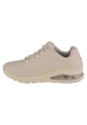Scarpa da ginnastica beige con una tomaia sintetica liscia, dettagli perforati, design con lacci e ammortizzazione ad aria trasparente nel tallone.