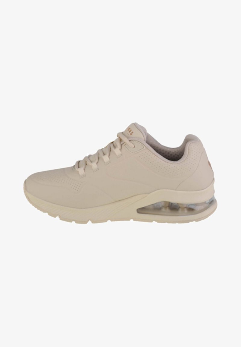 Zapatilla deportiva beige con parte superior sintética suave, acentos perforados, diseño de cordones y amortiguación de aire transparente en el talón.