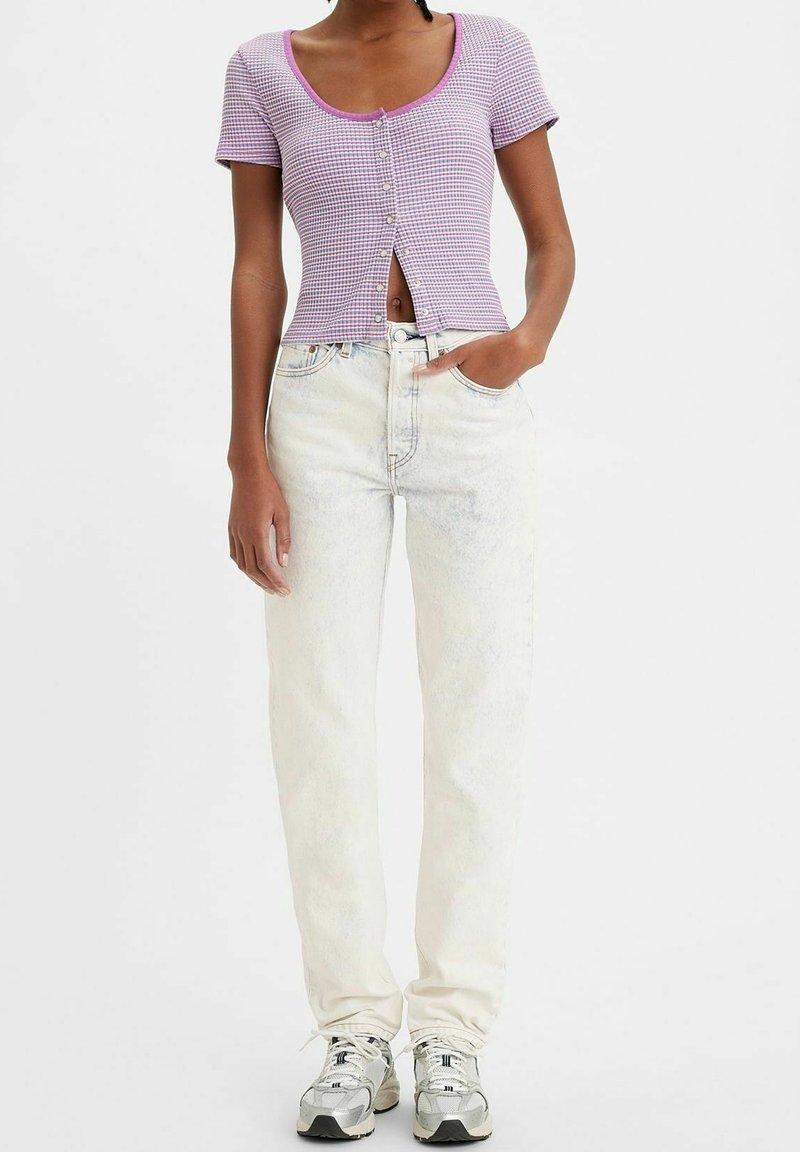 Haut court à manches courtes, à carreaux violets, avec des boutons, associé à un jean taille haute, coupe droite, délavé clair et des baskets grises.