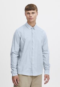 Lichtblauwe longsleeve shirt met button-down kraag, zachte katoenstof en normale pasvorm, gecombineerd met beige broeken.