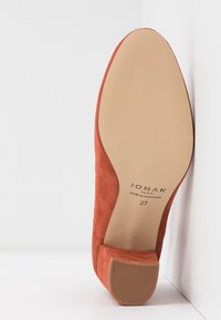 Chaussure pour femme en suède couleur rouille avec semelle beige lisse, petit talon carré, taille 37, fabriquée au Portugal, marque Jonak Paris.