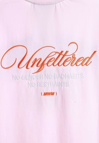 Camiseta de algodón rosa claro con un atrevido bordado en naranja y blanco. El texto dice "Sin restricciones SIN GÉNERO SIN MALOS HÁBITOS SIN LIMITACIONES (MWM)".