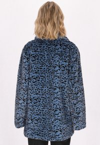 Chaqueta de pelo sintético azul con un patrón de leopardo negro, que presenta un corte relajado, mangas largas y un cuello. Textura suave.