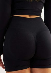Czarne, elastyczne szorty z wysokim stanem, o dopasowanym kroju i gładkiej teksturze, odpowiednie do aktywności. Brak widocznych logo.