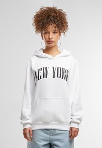 Felpa bianca con la scritta "NEW YORK" stampata in grandi lettere nere. Presenta una tasca frontale, cappuccio con stringa e polsini a costine, realizzata in un tessuto morbido.