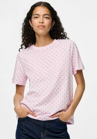 Vaaleanpunainen lyhythihainen t-paita, jossa on valkoinen pilkkukuosi. Paidan materiaali on pehmeä, ja siinä on rento istuvuus sekä pyöreä kaula-aukko.