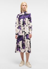 Abito a maniche lunghe con colletto in crema, caratterizzato da un grande motivo floreale viola e nero, con cintura in vita e una vestibilità rilassata, abbinato a sneakers chunky.