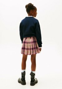Felpa navy, gonna plissettata a quadri rosa e stivaletti neri alla caviglia abbinati a calzini bianchi. Tessuto morbido e design classico con motivi distintivi.