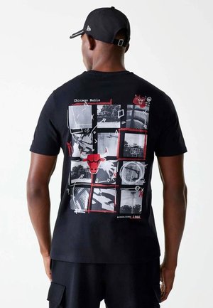 Mann trägt ein schwarzes Chicago Bulls T-Shirt mit Basketballfeld-Grafik und rotem Bullen-Logo, von hinten gesehen.