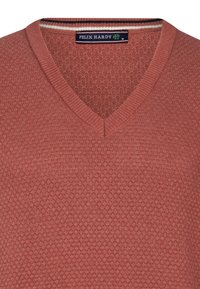 Suéter de pico en terracota con un patrón de punto texturizado. Presenta bordes acanalados y una etiqueta con el nombre de la marca.