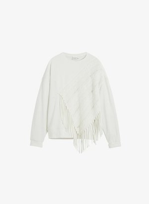 Valge dressipluus, millel on tekstuurist, kootud ponšo overlay, millel on friteeritud äär. Disain on vabalt istuv ja pika varrukaga.