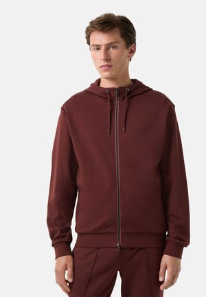 Bordeaux zip-up hoodie van zacht materiaal, met een capuchon, trekkoorden en geribbelde manchetten. Gecombineerd met bijpassende broeken.