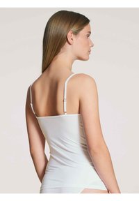 White camisole with thin adjustable straps, fitted design, smooth texture, and no visible patterns or embellishments.
