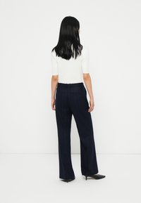 Navy pinstriped trousers with a tailored fit, made of woven fabric. High waist, side pockets, and a clean finish with a smooth texture.