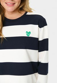 Tumesinine ja valge triibuline sweatshirt, millel on ümar kaelus. Rinnas on roheline süda, millel on tikitud sõna "armastus". Pehme tekstuur.