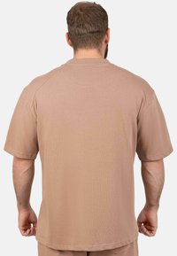 T-shirt marron à manches courtes et col rond, fabriqué en tissu doux et texturé, avec une coupe décontractée et un ourlet cousu. Vue de dos montrant peu de détails.