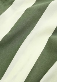 Bavlněná tkanina s alternativními olivově zelenými a smetanovými pruhy, která má hladkou texturu a mírný lesk, vytvářející jemnou hloubku.
