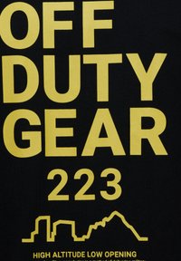 Svart tyg med fet gul text som läser "OFF DUTY GEAR 223." Inkluderar en stadsbilds-grafik och ytterligare text under.