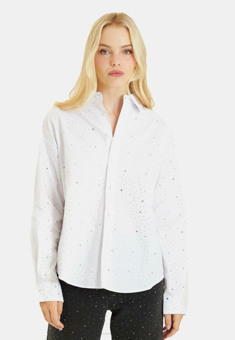 Camicia bianca con colletto e decorazioni in argento sparse. Maniche lunghe e vestibilità leggermente ampia. Tessuto leggero.