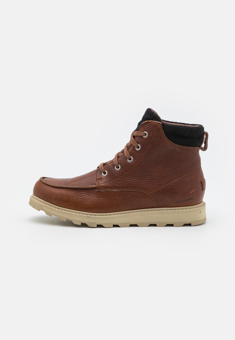 Bottes chelsea en cuir brun avec une finition texturée, un col noir contrastant, une semelle en caoutchouc crème et des œillets en métal pour les lacets.