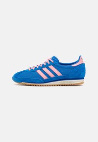 Sapatilha desportiva azul com detalhes em rosa, apresentando um upper em malha, três riscas rosas, pormenores em camurça e uma sola de borracha de gengibre.