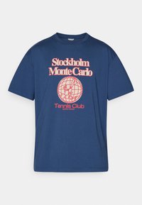 Marineblå bomulds t-shirt med rund hals. Har hvid retro tekst og grafisk billede af en globe. Løs pasform med korte ærmer.