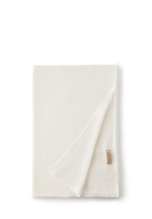Couverture en polaire blanche avec une texture douce, dotée d'un ourlet subtil et d'une petite étiquette dans le coin.