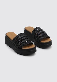 Sandalias de plataforma negras con tiras trenzadas y un acabado texturizado. Plantilla marrón, suela de goma duradera y forma de punta redondeada.
