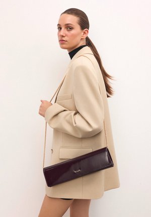 Violette Clutch aus Lackleder mit einem goldenen Kettenriemen, rechteckiger Form, glatter Textur und einem kleinen Logodetail auf der Vorderseite.