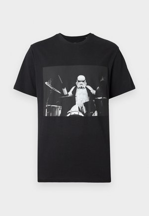 Black cotton t-shirt featuring a frontal graphic of a stormtrooper playing drums, highlighting the shirt's casual, relaxed fit.