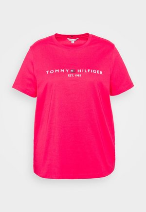 Lyserød T-shirt med korte ærmer med hvid "Tommy Hilfiger Est. 1985" tekst og logo centreret på brystet.
