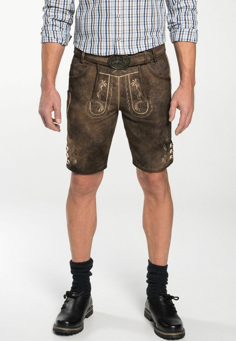 Braune Ledershorts mit dekorativer Stickerei, strukturiertem Finish und Knopfakzenten. Kombiniert mit einem karierten Hemd und schwarzen Schuhen.