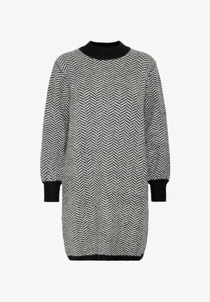 Juoda ir balta chevron rašto megztinė suknelė su aukštu kaklu, ilgesnėmis rankovėmis ir nertais rankogaliais. Lygus tekstūros paviršius ir laisvas siluetas.