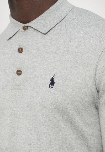 Szürke póló puha anyagból, klasszikus gallérral, három barna gombbal és egy kis tengerészkék ló- és lovaslogóval.