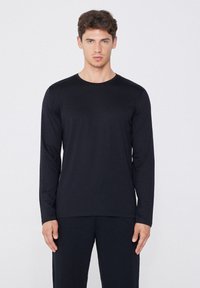 Schwarzes Langarmshirt aus glattem Stoff, mit runder Ausschnitt und figurbetonter Silhouette. Strukturierten Bündchen und Saum.