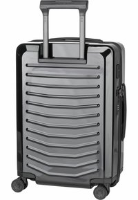 Valigia rigida di colore grigio lucido, con design rigato, manico telescopico e quattro ruote girevoli per una maggiore mobilità. Include cerniera e lucchetto.