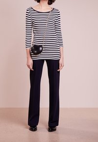 Mustat ja valkoiset raidalliset pitkät hihat, yhdistettynä laajahelmaisiin tummansinisiin housuihin. Asusteina musta sydämenmuotoinen laukku ketjuhihnalla.