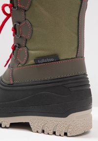 Zielony, wodoodporny but z czarną gumową podeszwą. Posiada czerwone sznurówki, kontrastujące przeszycia oraz teksturowany panel dla lepszej przyczepności. Widoczna metka marki.