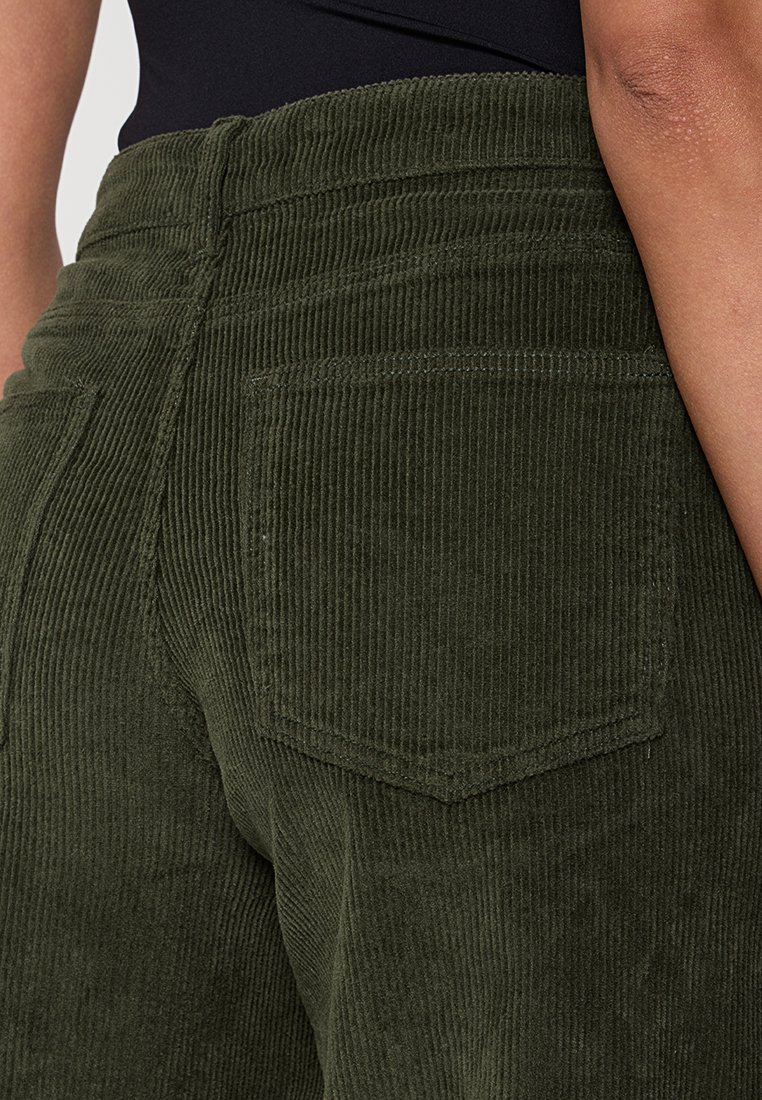 Groene corduroy broek met een geribde textuur, voorzien van een achterzak en een hoge taille. De slim-fit benadrukt de vormen.