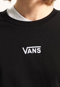 Black cotton t-shirt with a ribbed crew neckline, featuring a white embroidered "VANS" logo on the chest. Simple, classic design.