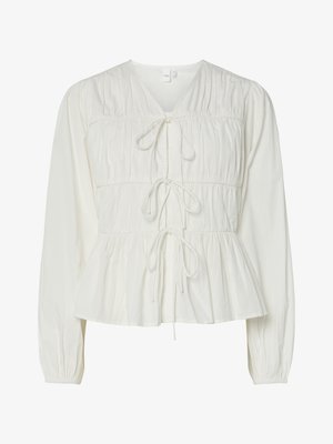 Biely dlhý rukáv blúzka s tromi prednými viazacími uzávermi, zberané tkaninové detaily, elastické manžety a lem v štýle peplum.